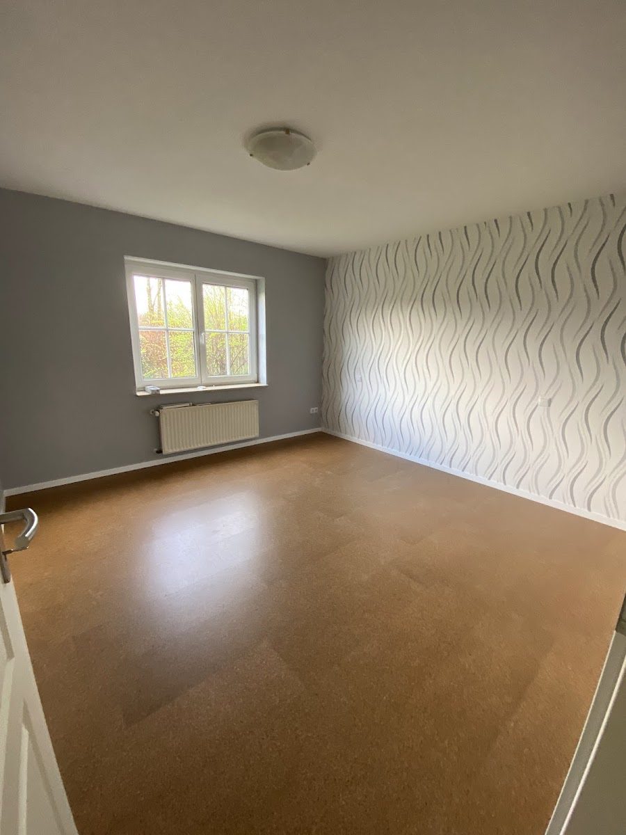 Zimmer mit heller Strukturtapete und warmem Boden